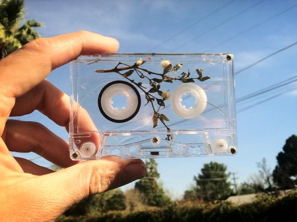 Hand holding a cassette tape against blue sky